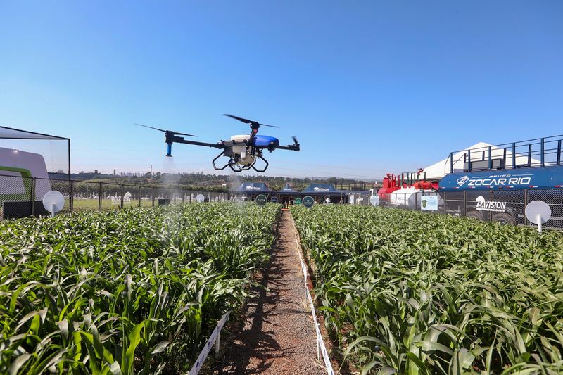 Drone pertanian melayang di atas barisan tanaman saat demonstrasi di lapangan terbuka